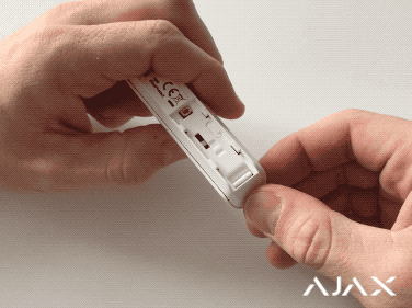 Image of a person replacing the battery of an Ajax DoorProtect device at home for easy DIY options